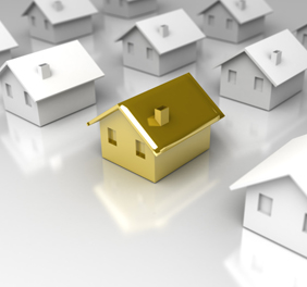 Image of a gold toy house amidst white toy houses